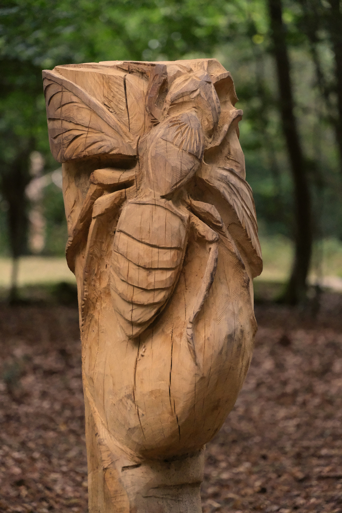 a wooden sculpture of a hornet in the woods